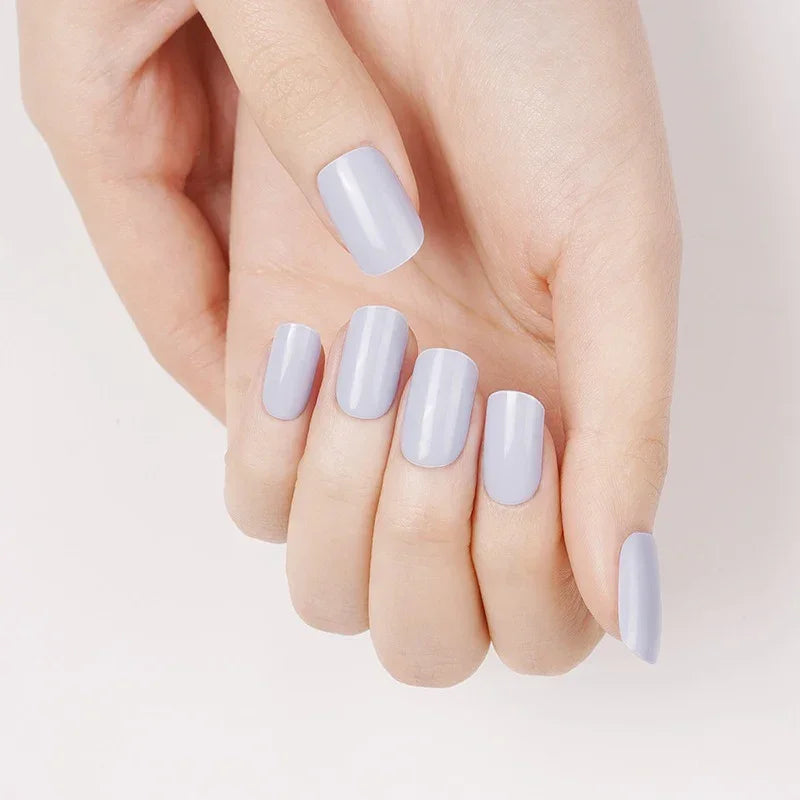 Semi-cured gel nail wraps in pastel periwinkle with a creamy lavender-blue hue and smooth glossy finish, shown on fair skin under soft daylight.