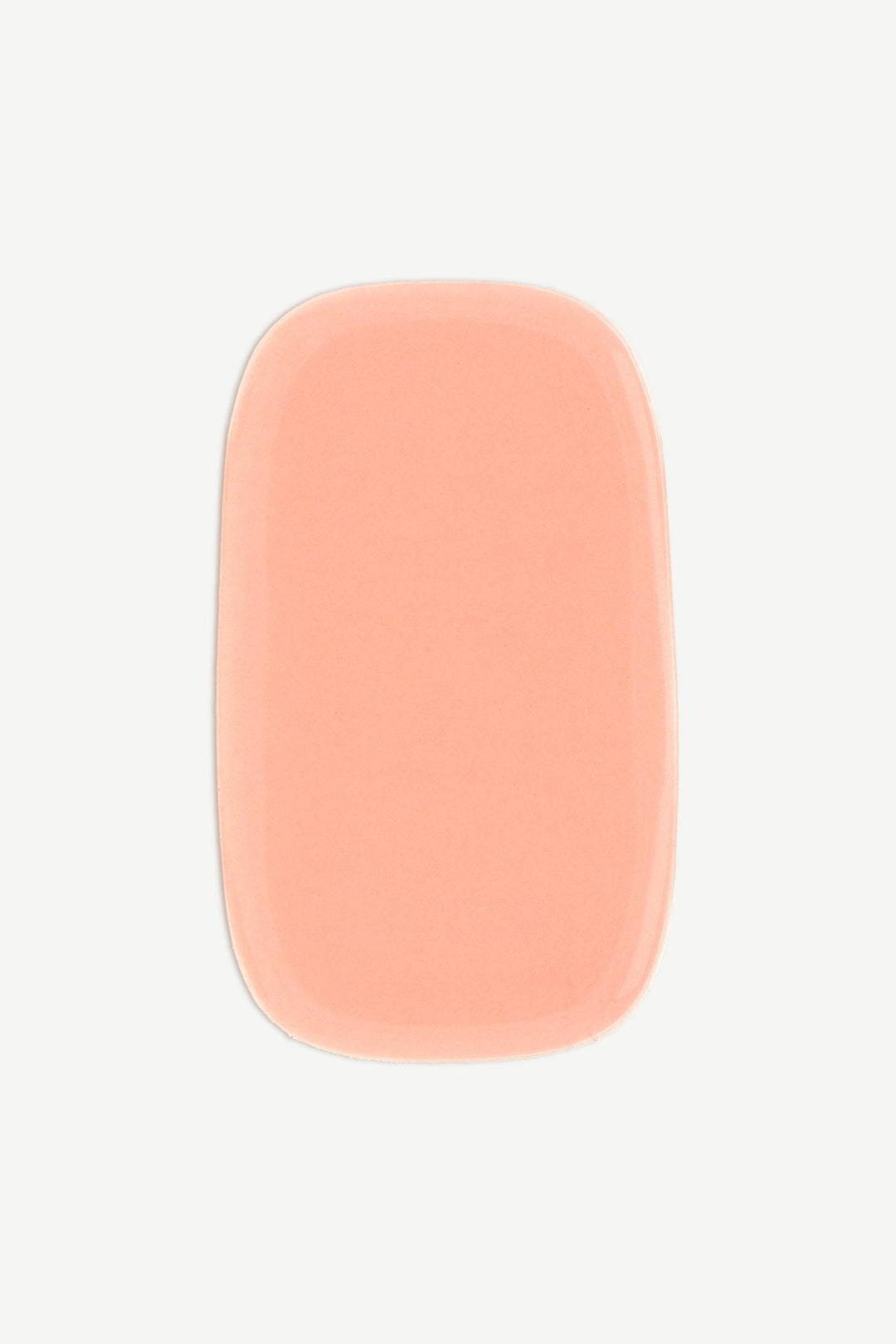A macro image of a perfect peach stick-on gel nail strip showing a smooth, semi-transparent texture and high-gloss shine.