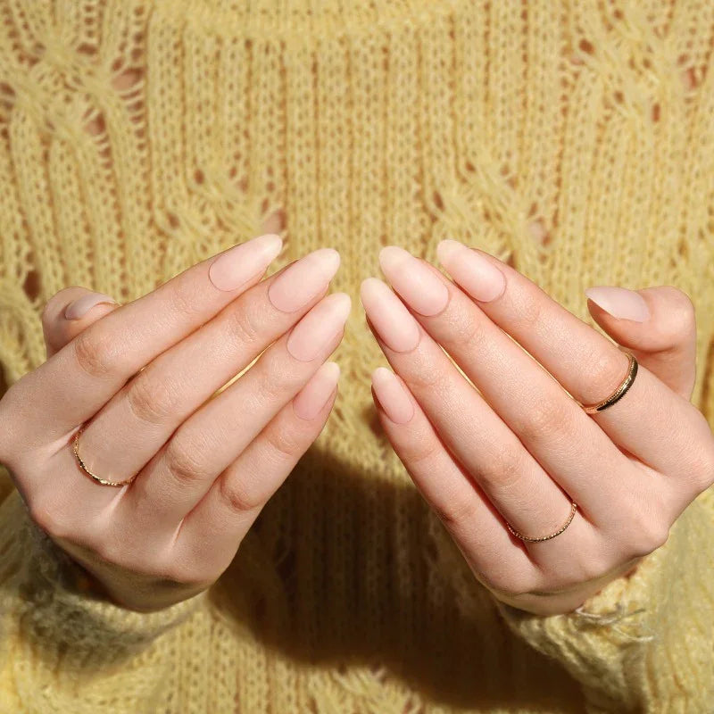 Semi-cured gel nail wraps in nude-pink matte tones, displayed on hands against a cozy yellow knit sweater.