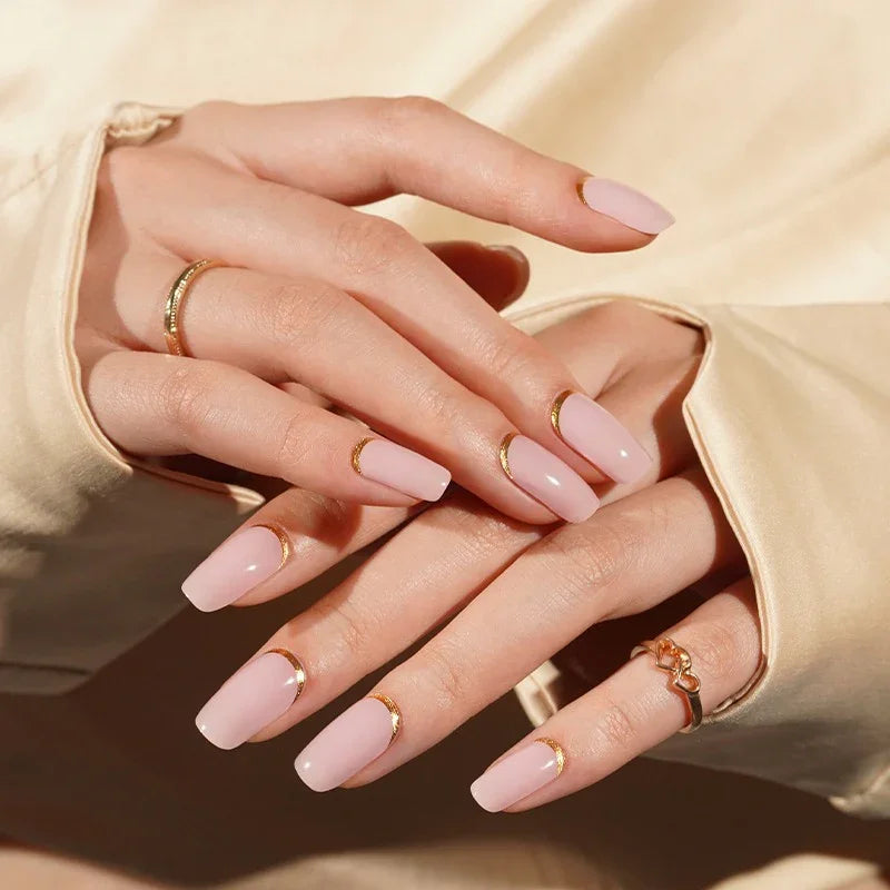Hands with Pink Moon gel nail wraps in soft nude-pink, accented with metallic gold cuticle cuffs and a glossy, luminous finish.
