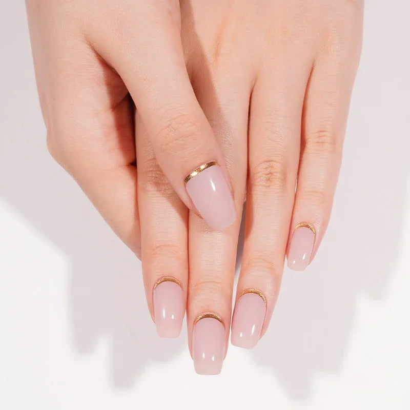 Hands wearing Pink Moon gel nail wraps in glossy nude-pink with gold cuticle cuffs, shown in soft natural lighting.