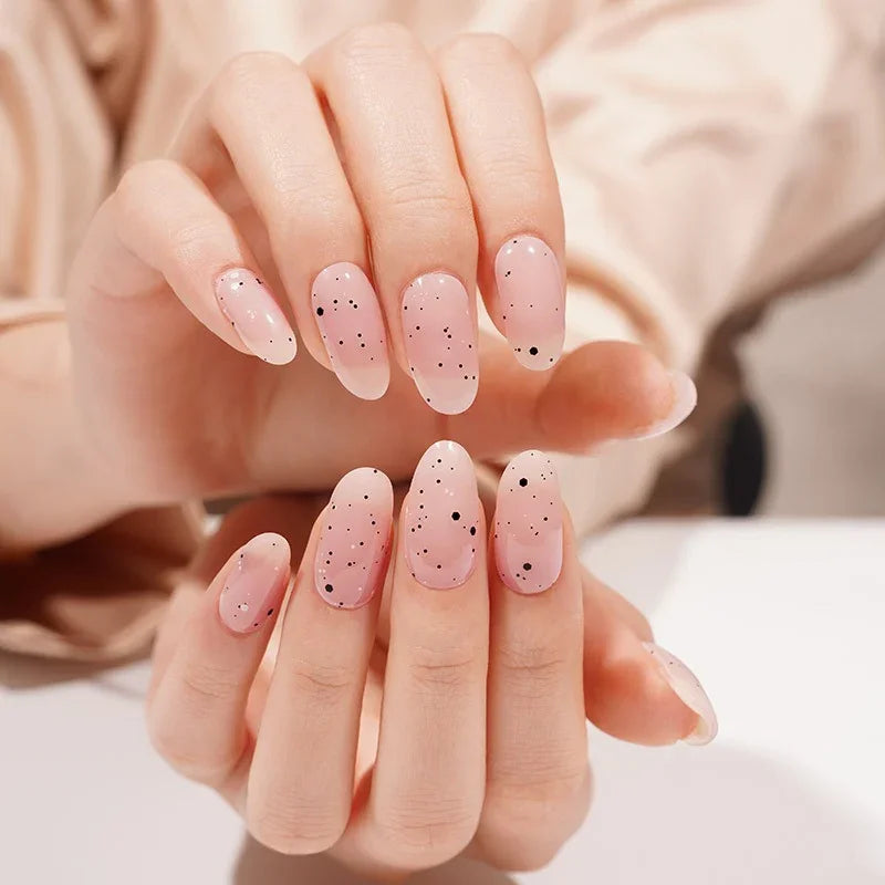 Hands with Pink Speckled Eggs gel nail wraps in sheer pink, featuring delicate black speckles and a high-gloss finish.