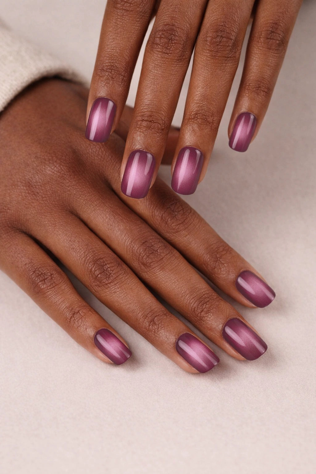 Plum Ombré semi-cured gel nail stickers, shown on medium-deep brown skin with a smooth plum-to-soft-pink gradient and a glossy finish, photographed under soft studio lighting against a neutral cream backdrop.