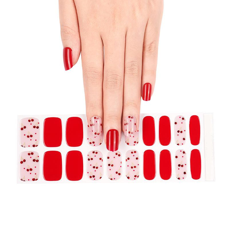 Sheet of red and pink gel nail strips with metallic cherry accents in glossy finish, displayed on white background.