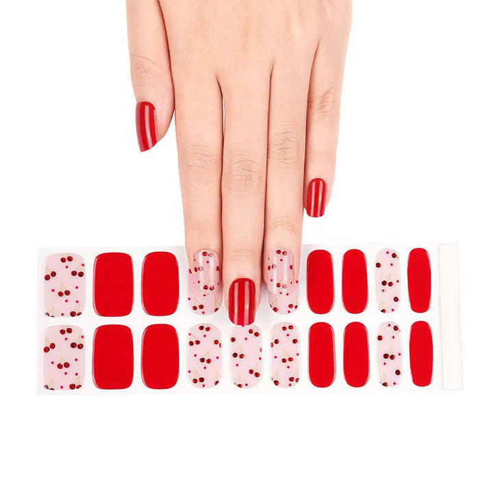 Sheet of red and pink gel nail strips with metallic cherry accents in glossy finish, displayed on white background.