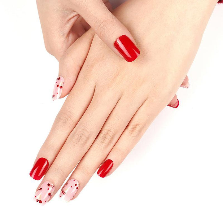 Soft pink and bright red gel nail stickers with metallic red cherry accents and on light skin tone in natural light.