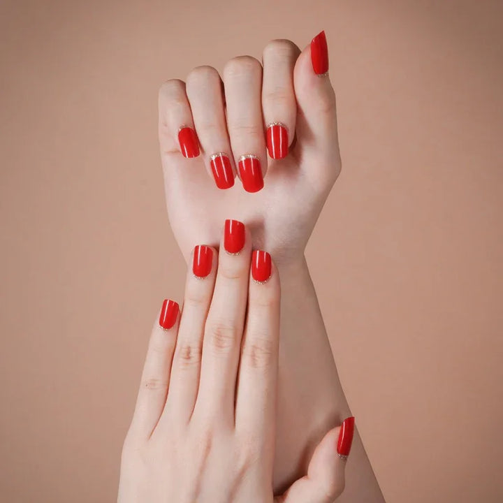 Close-up of hands wearing Red Moon gel nail wraps in glossy red with golden cuticle accents, highlighting the rich color and high-shine finish.