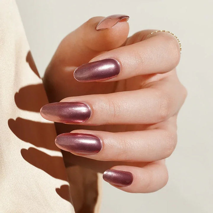 Rose Quartz semi-cured gel nail stickers in a metallic pink shade with a slight sheer transparency, shown under soft natural-style lighting on light skin with a delicate gold ring and a cream blouse.
