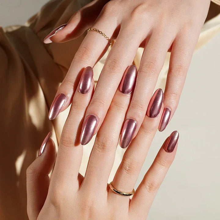 Rose Quartz pink semi-cured gel nail stickers in a reflective rose-pink metallic finish, photographed under soft natural-style lighting on light skin with gold rings and a cream satin blouse.