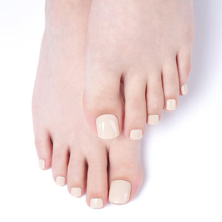 Feet with sandstone beige gel toenail wraps in a warm neutral tone and glossy finish.