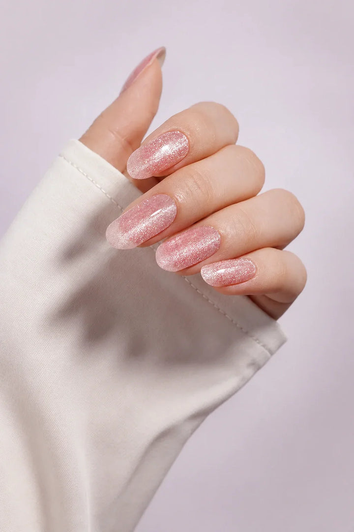 Sheer Blush Cat Eye UV-free gel nail wraps in a soft translucent blush pink with fine shimmer and a luminous cat-eye effect, with a glossy finish, shown on light skin.
