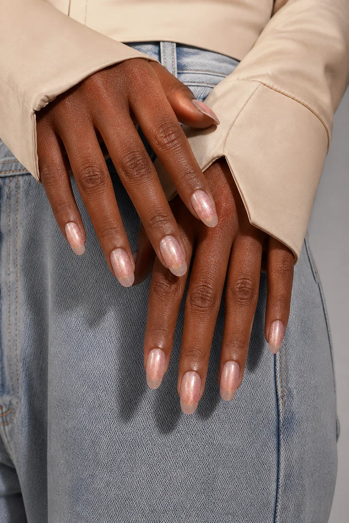 UV-free gel nail wraps in a soft blush pink with fine pearlescent cat-eye shimmer and a glossy finish, shown on dark skin.