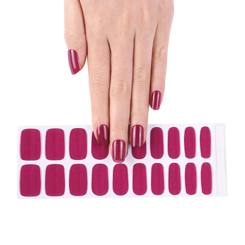 Sheet of shimmering magenta gel nail stickers displayed with matching manicured hand on neutral background.