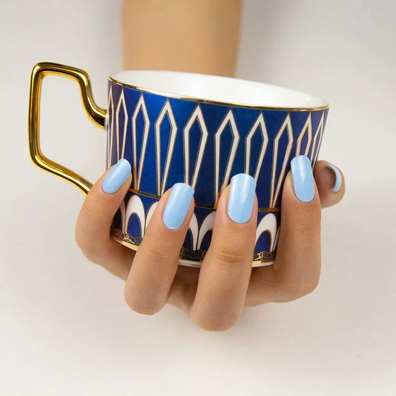 Semi-cured gel nail wraps in soft sky-blue with a smooth, glossy pastel finish, shown on medium-tan skin with neatly manicured nails.