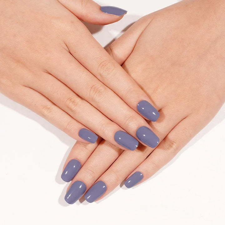 Slate Blue semi-cured gel nail stickers in a cool muted blue shade with a glossy finish, photographed under bright diffused studio lighting on light skin against a clean white background.