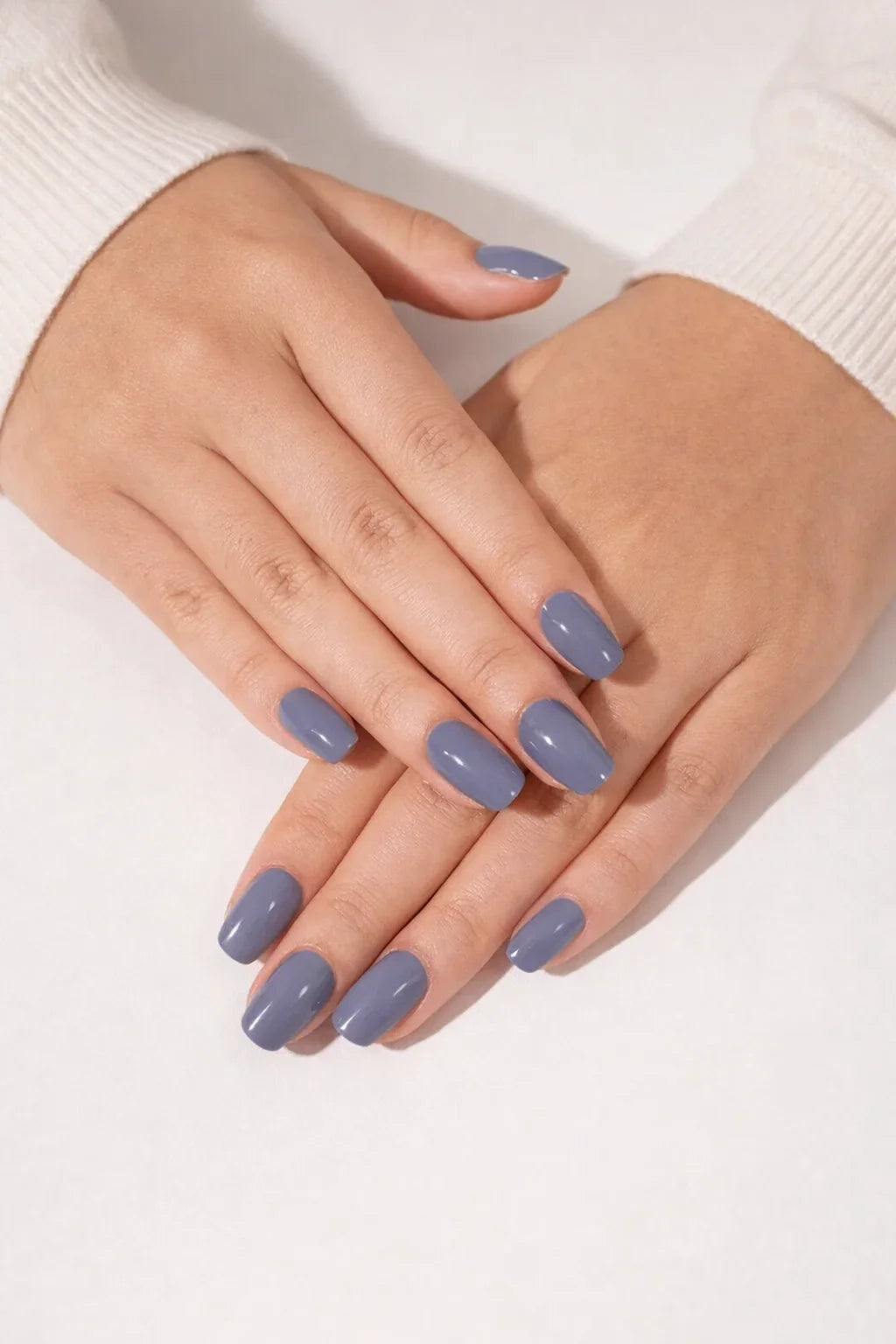 Slate Blue semi-cured gel nail stickers in a cool muted blue shade with a glossy finish, photographed under bright diffused studio lighting on light skin against a clean white background.