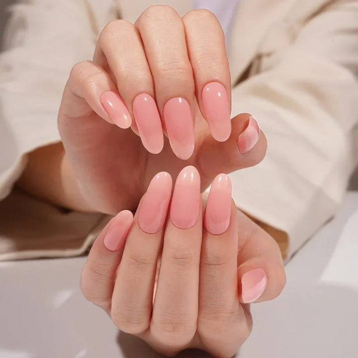 Semi-cured gel nail wraps in milky pink with a soft translucent tone and high-gloss finish, shown on light-medium skin in neutral cream clothing.