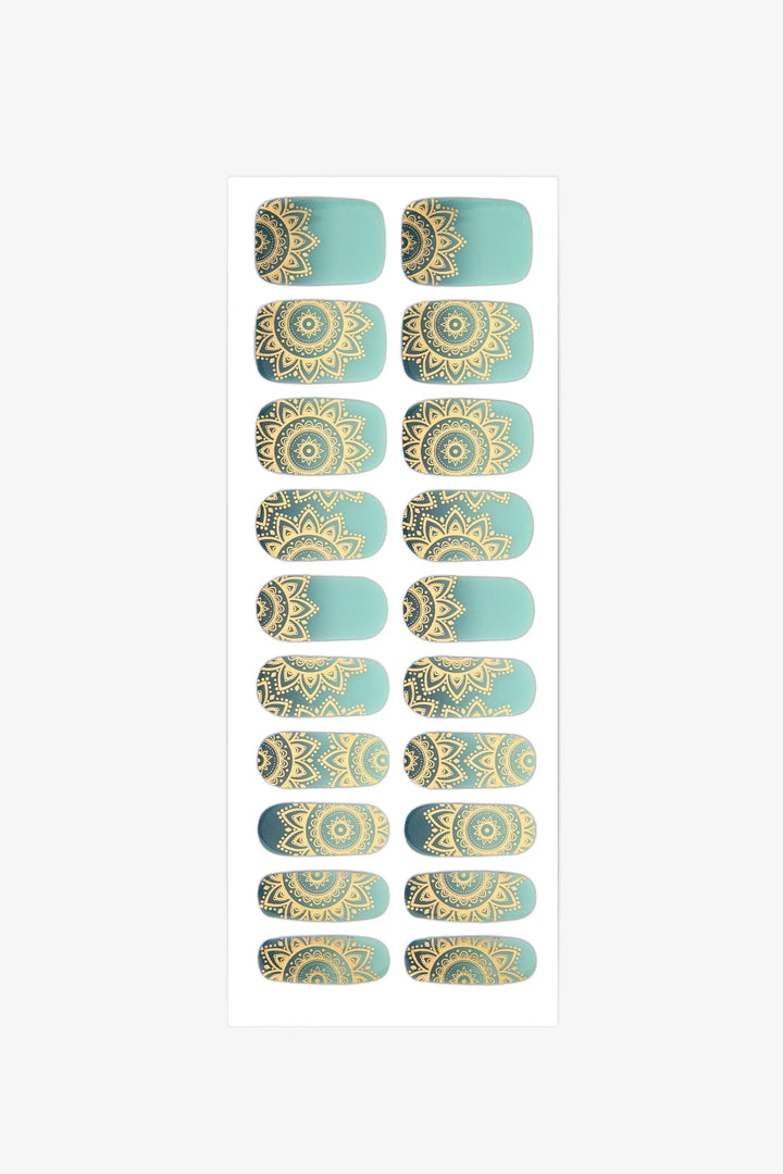 Sheet of semi-cured gel nail wraps in teal-to-aqua gradient with gold mandala details and a glossy surface.