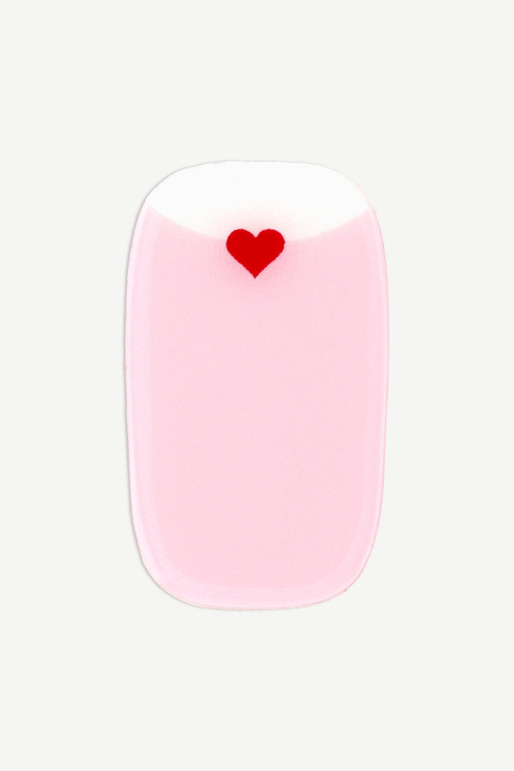 Close-up of a soft pink gel nail wrap with a tiny red heart detail near the transparent cuticle area.