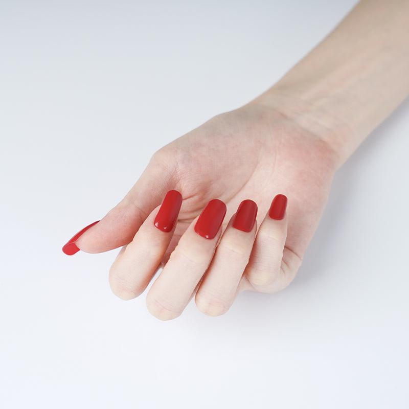 Rich red gel nail stickers with glossy finish on light skin tone, photographed under soft light.